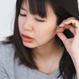 Woman scratches ear