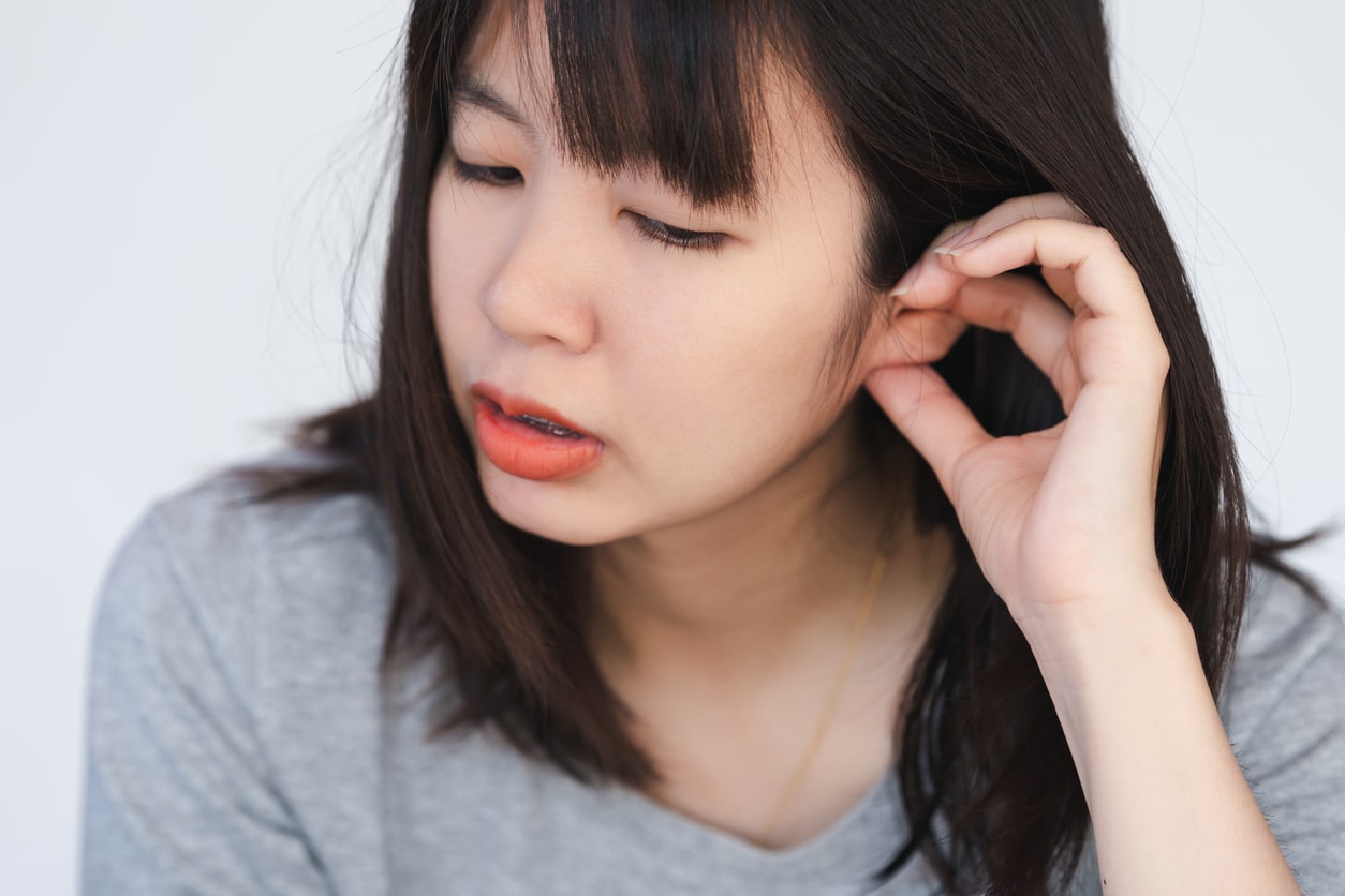 Woman scratches ear
