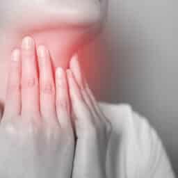 Throat pain concept, girl holding her red throat