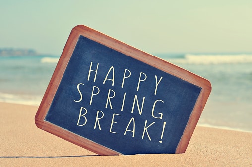 Happy spring break written in a blackboard on the sand of a beach, with a filter effect.