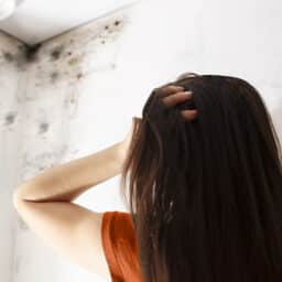 Woman staring at the mold growing in the corner of her ceiling.